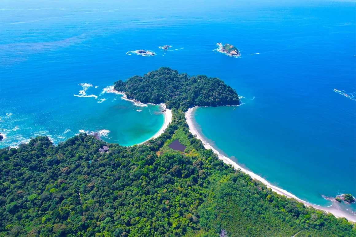 Aerial view of a lush Costa Rica coastline with twin crescent beaches and bright blue water.
