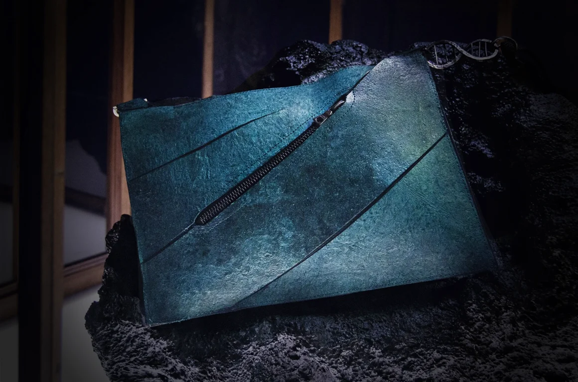 The one-of-a-kind T-Rex Leather handbag displayed on a dark rock-textured pedestal during the Amsterdam unveiling.