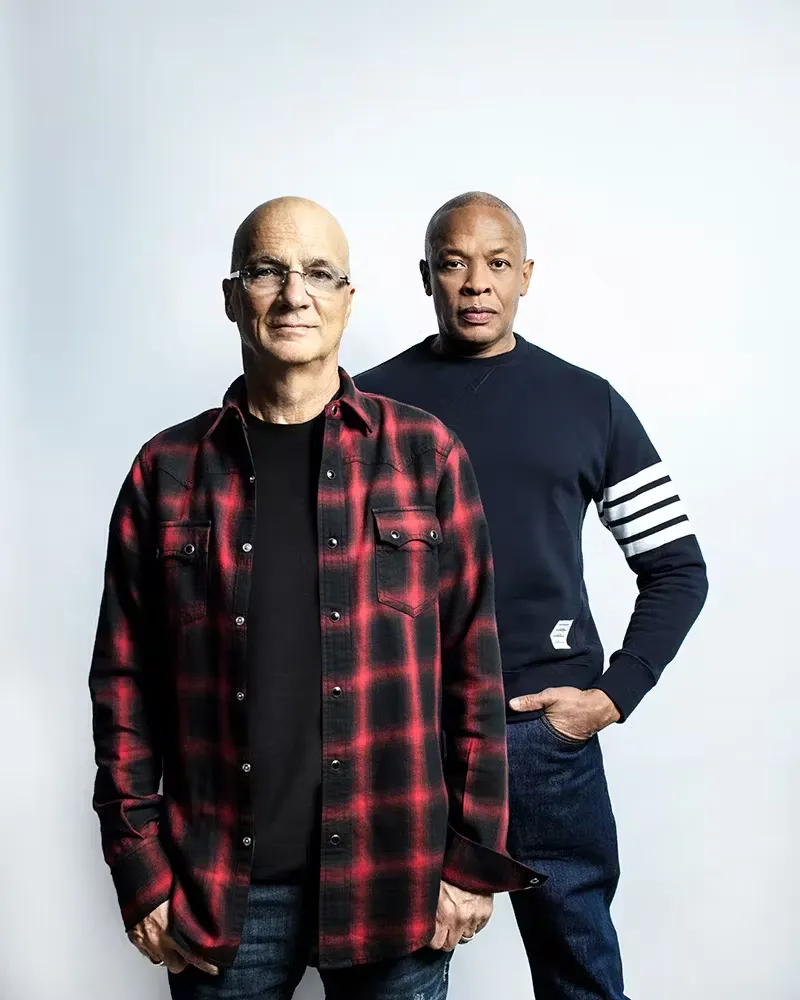 Jimmy Iovine and Dr. Dre standing side by side in a studio-style portrait against a neutral background