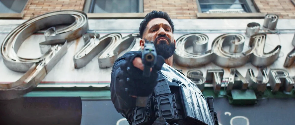 Jon Bernthal as Punisher standing in a dimly lit scene with a serious expression