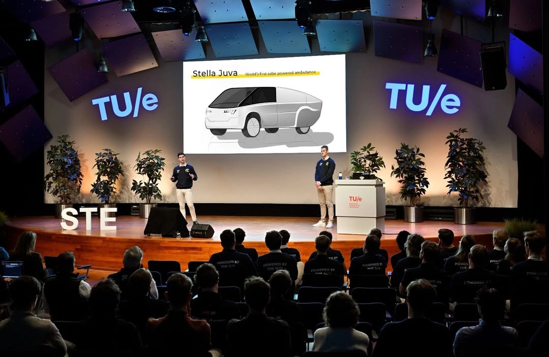 Solar Team Eindhoven presents the Stella Juva solar ambulance concept on stage at TU/e, with the vehicle design shown on a large screen.
