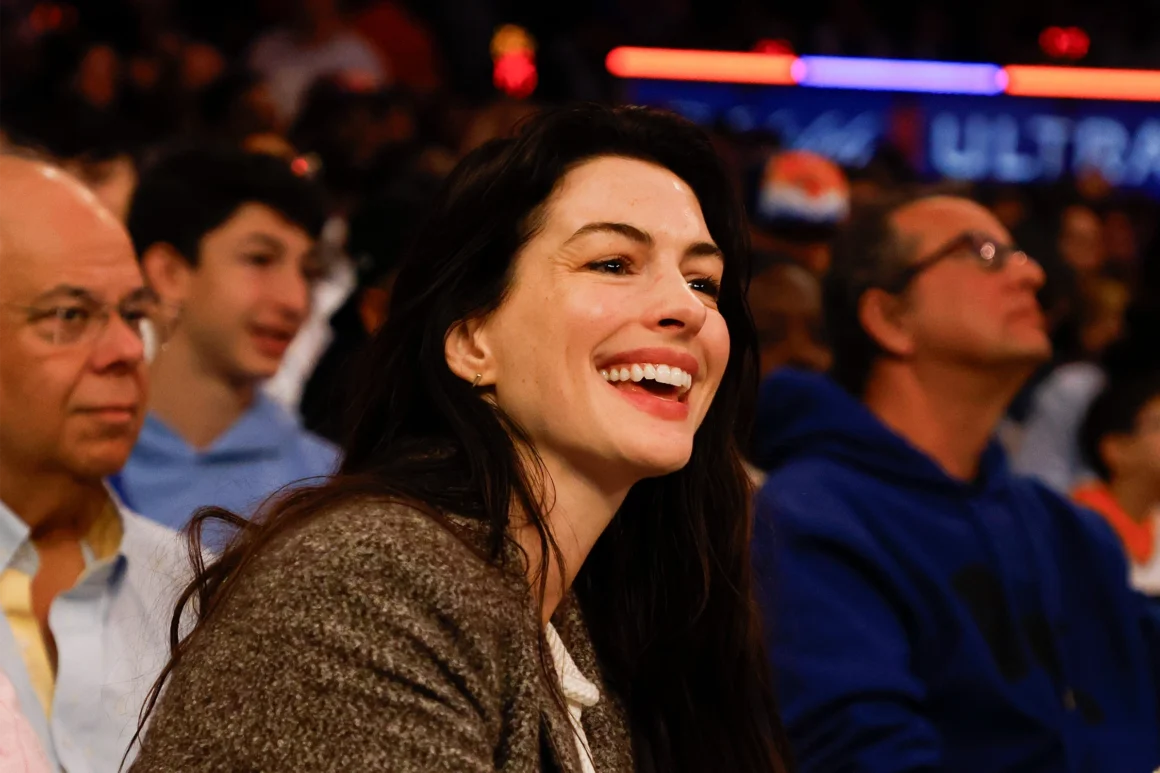 Anne Hathaway 2026 Knicks courtside visibility as she smiles during a Madison Square Garden basketball game.