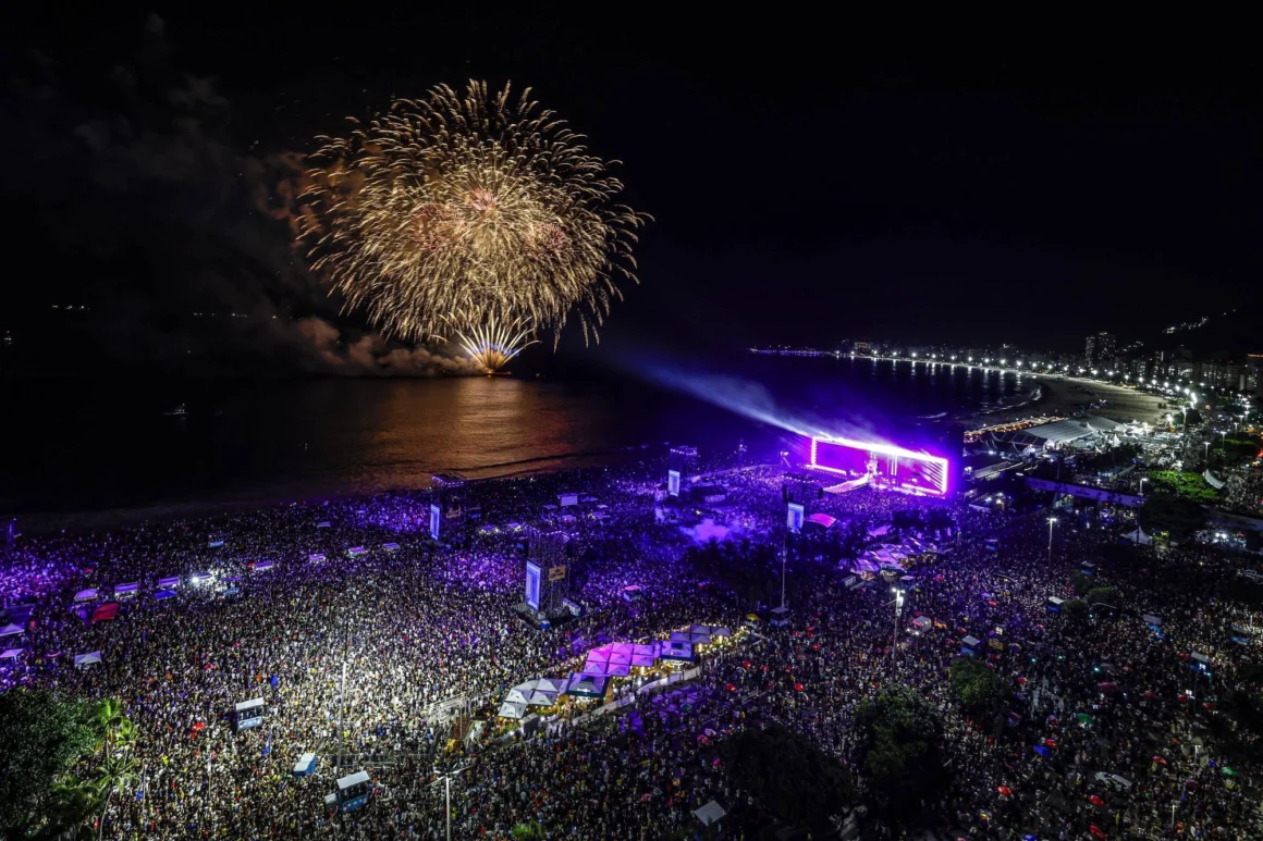 Aerial night view of Shakira Copacabana concert with stage lights and a massive crowd on Rio beach