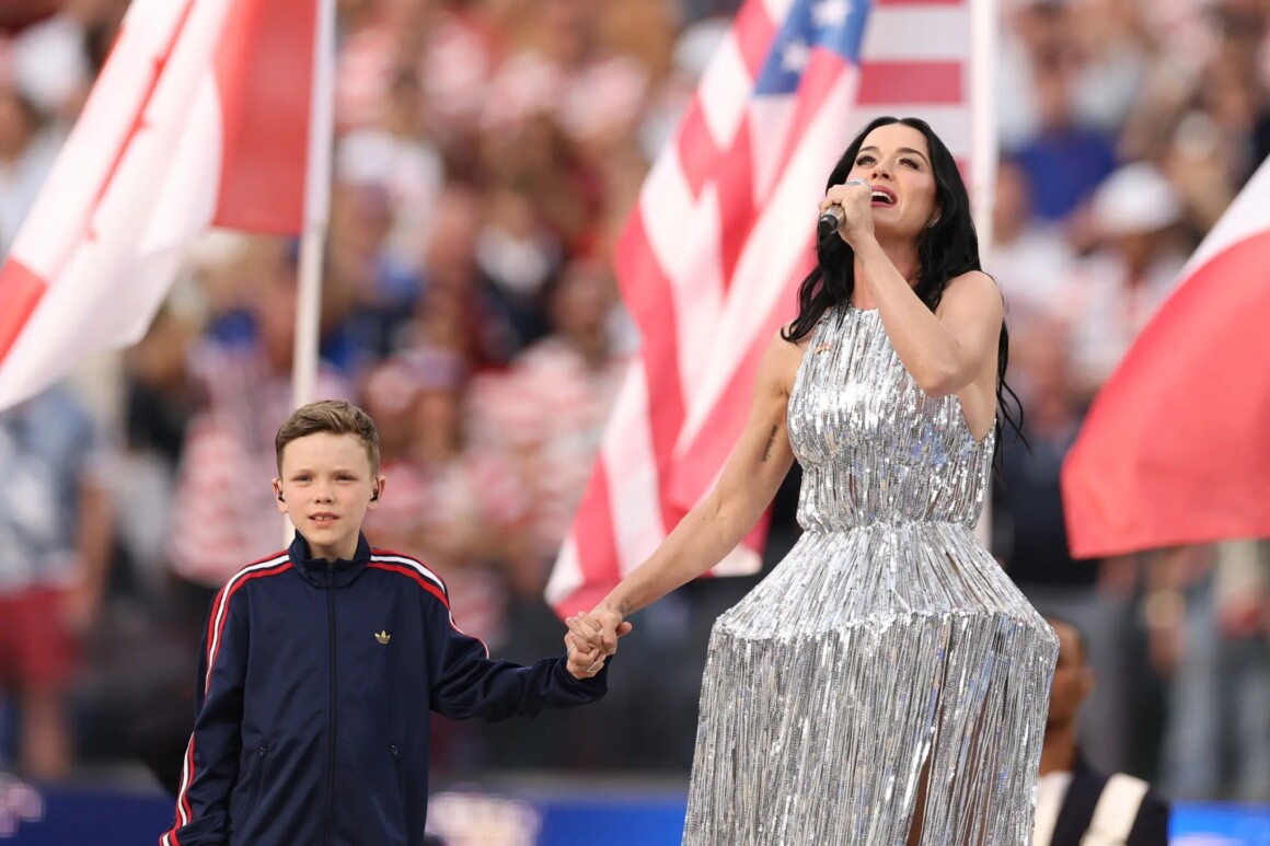 A singer holds hands with a young guest performer during the World Cup opening ceremony.